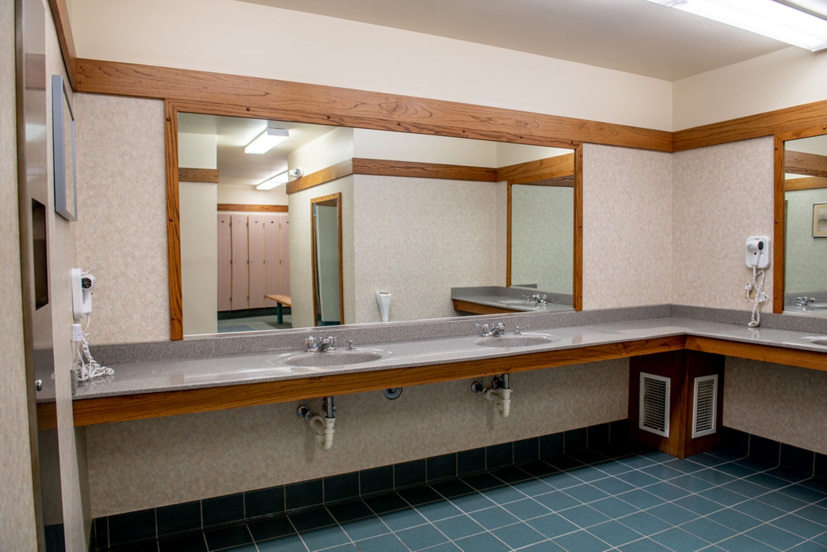 A public restroom with two sinks, wooden accents, and a mirror.