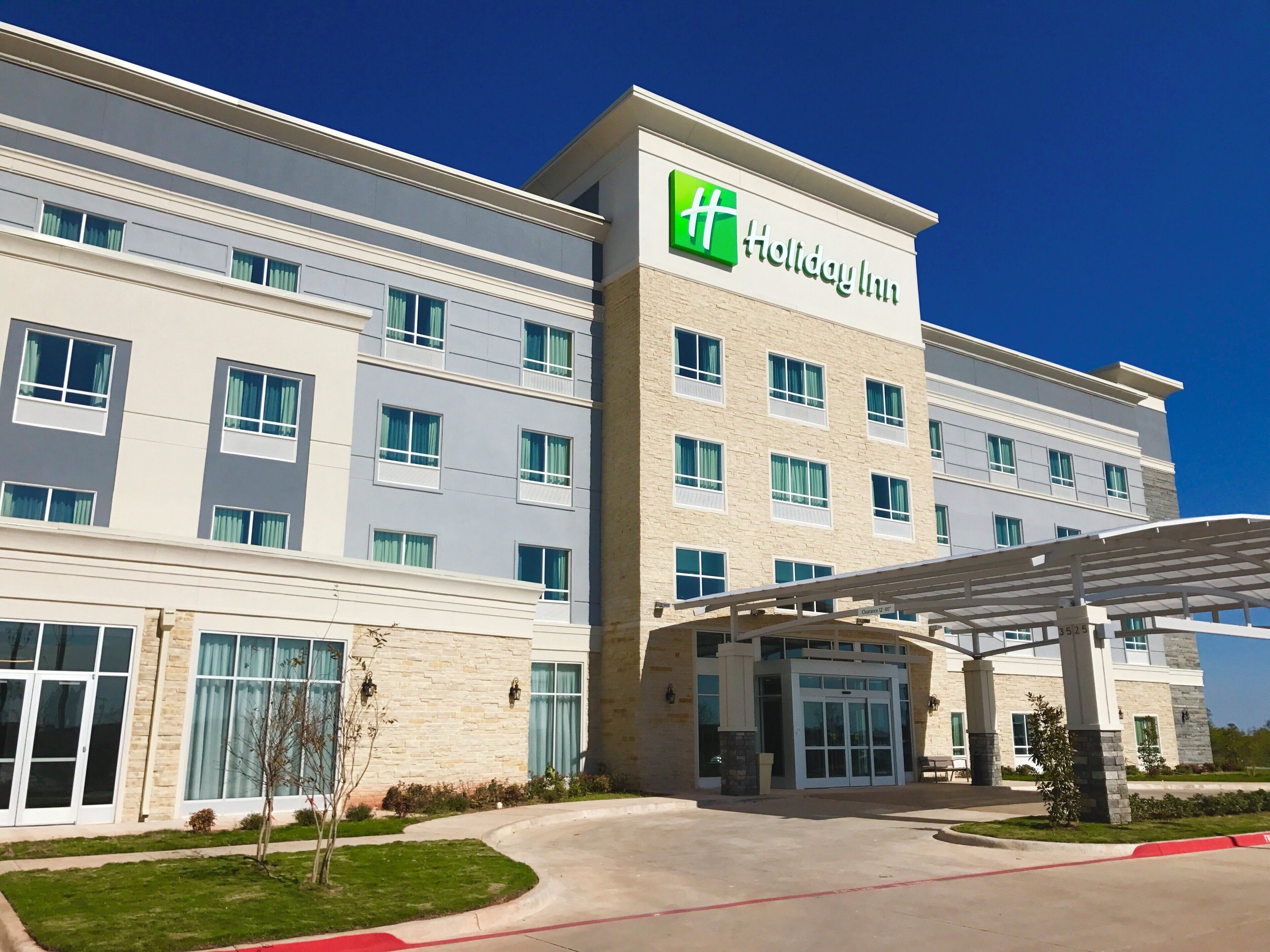 A Holiday Inn hotel with a modern facade, large windows, and a covered entrance.