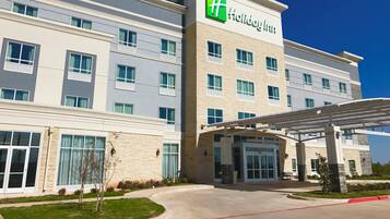 A Holiday Inn hotel with a modern facade, large windows, and a covered entrance.