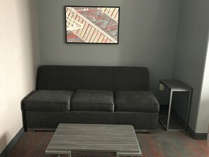 Une pièce moderne avec un canapé gris, une petite table et un tableau encadré accroché au mur.