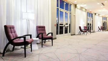A hotel lobby with seating areas, a reception desk, and large windows.