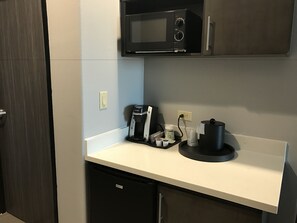 Une petite cuisine équipée d’un four à micro-ondes, d’une machine à café et d’un petit réfrigérateur.