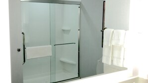 Une salle de bain avec un grand miroir, une douche à parois de verre et un lavabo blanc.