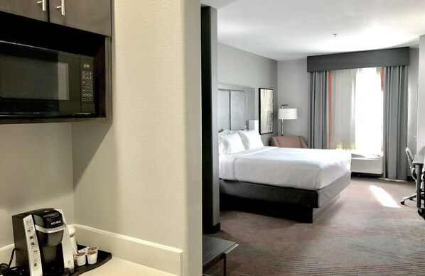 A hotel room with a bed, bedside table, lamp, and a microwave. - Holiday Inn Abilene - North College Area by IHG (Abilene)