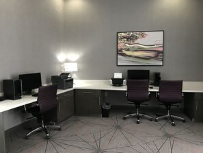 Un bureau moderne équipé de deux bureaux, deux chaises, une imprimante et d’un grand tableau abstrait accroché au mur.