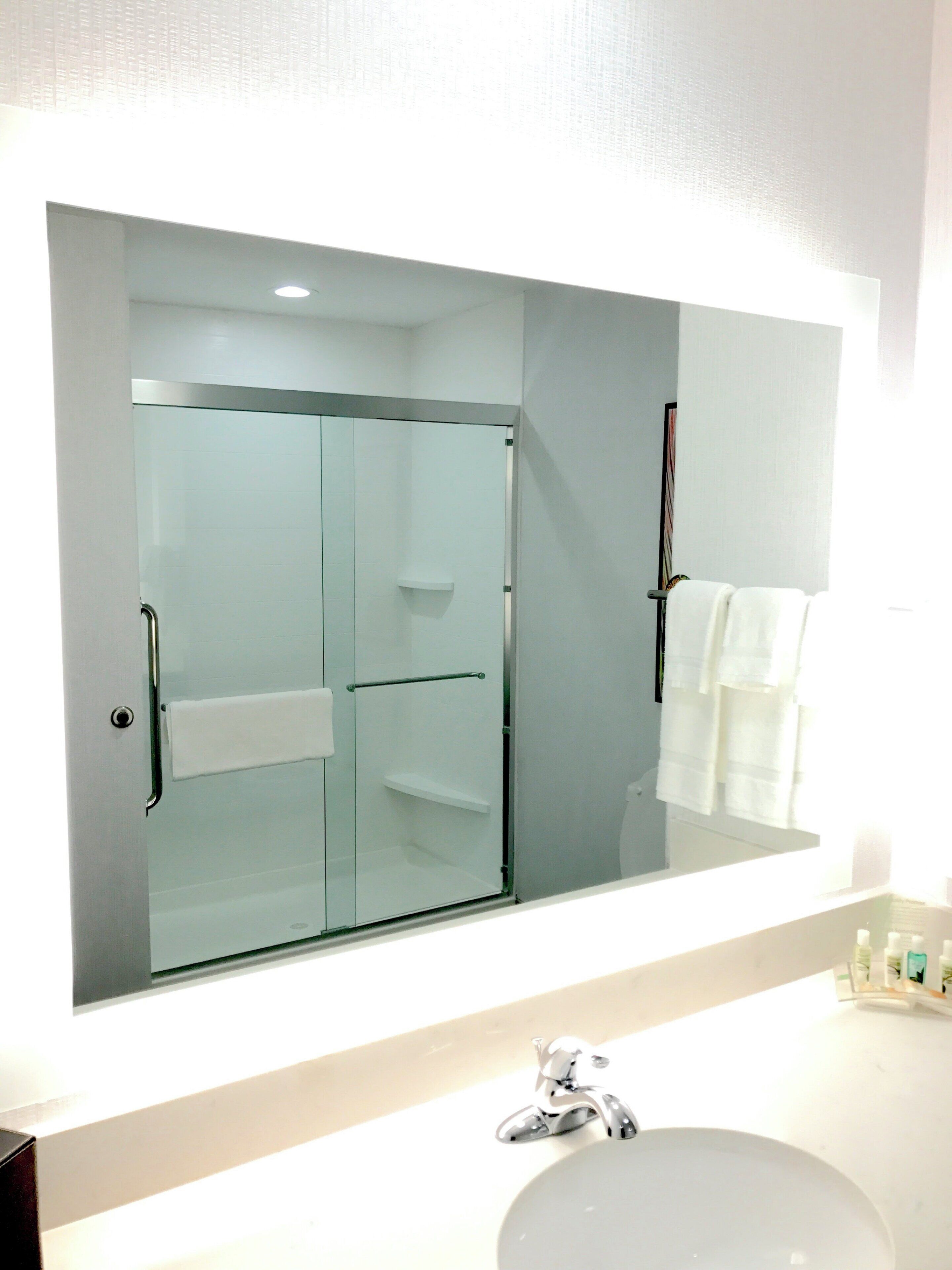 Une salle de bain avec une douche à parois de verre, un lavabo blanc et un miroir au-dessus du lavabo.