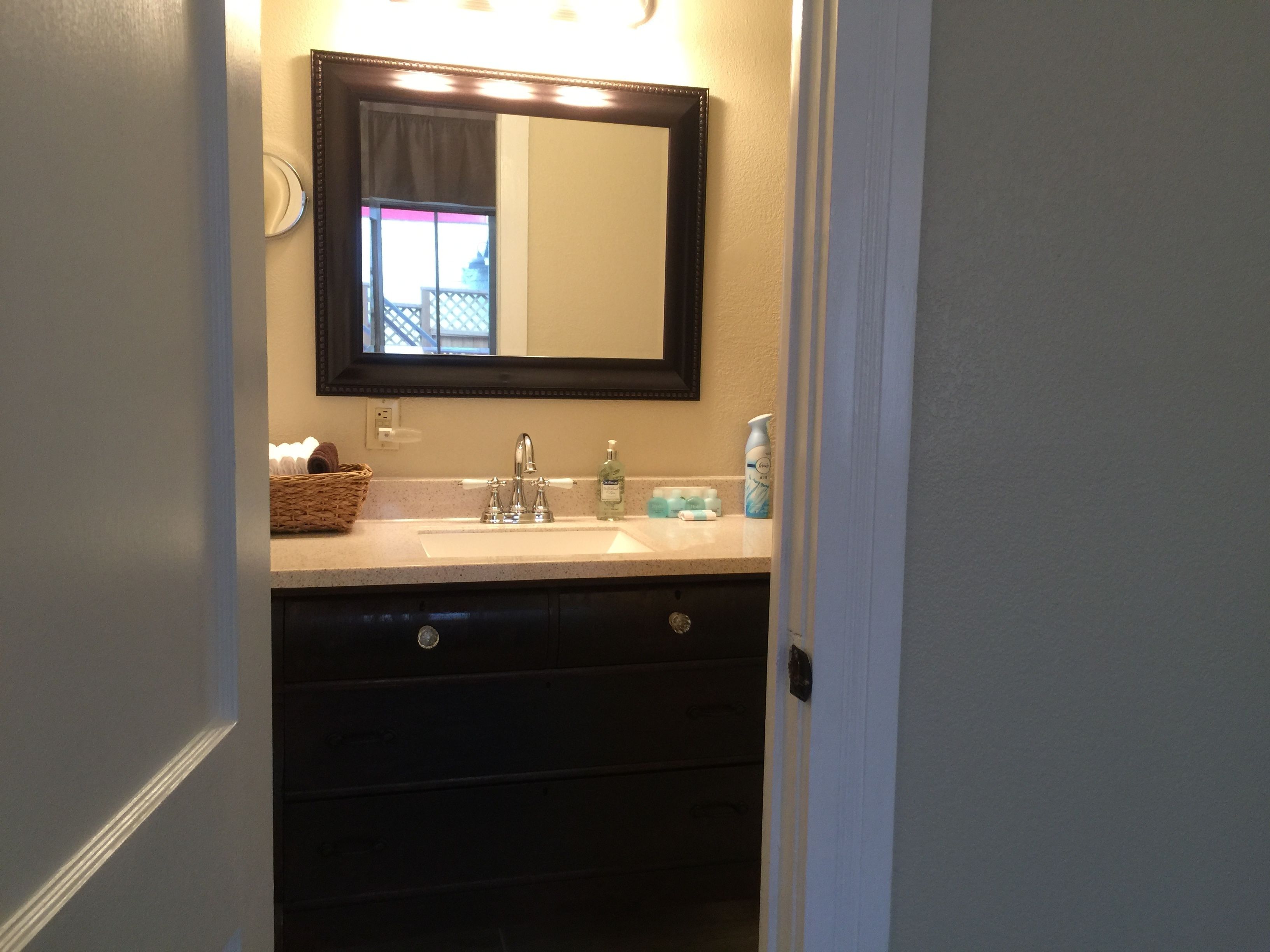 A bathroom with a sink, mirror, and dark-colored cabinet.