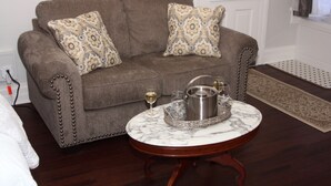 A living room with a brown sofa, patterned cushions, a marble coffee table, and a tray with a pot and glasses. - Elmwood House (Eureka Springs)