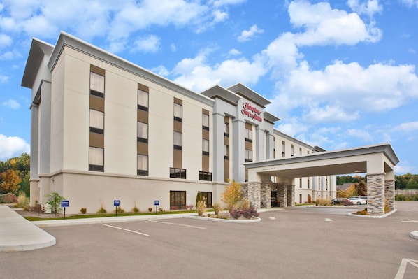 Welcome to Hampton Inn & Suites, featuring a symmetrical facade with multiple windows and a covered walkway leading to the main entrance.