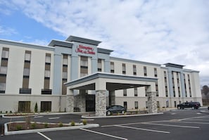 Hampton Inn & Suites features a symmetrical facade with a flat roof and grid-patterned windows.