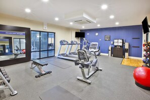 Une salle de sport équipée de tapis de course, de vélos elliptiques et de poids libres.