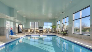 An indoor swimming pool with clear blue water, surrounded by seating areas and large windows. - Hampton Inn & Suites Chicago Schaumburg (Schaumburg)