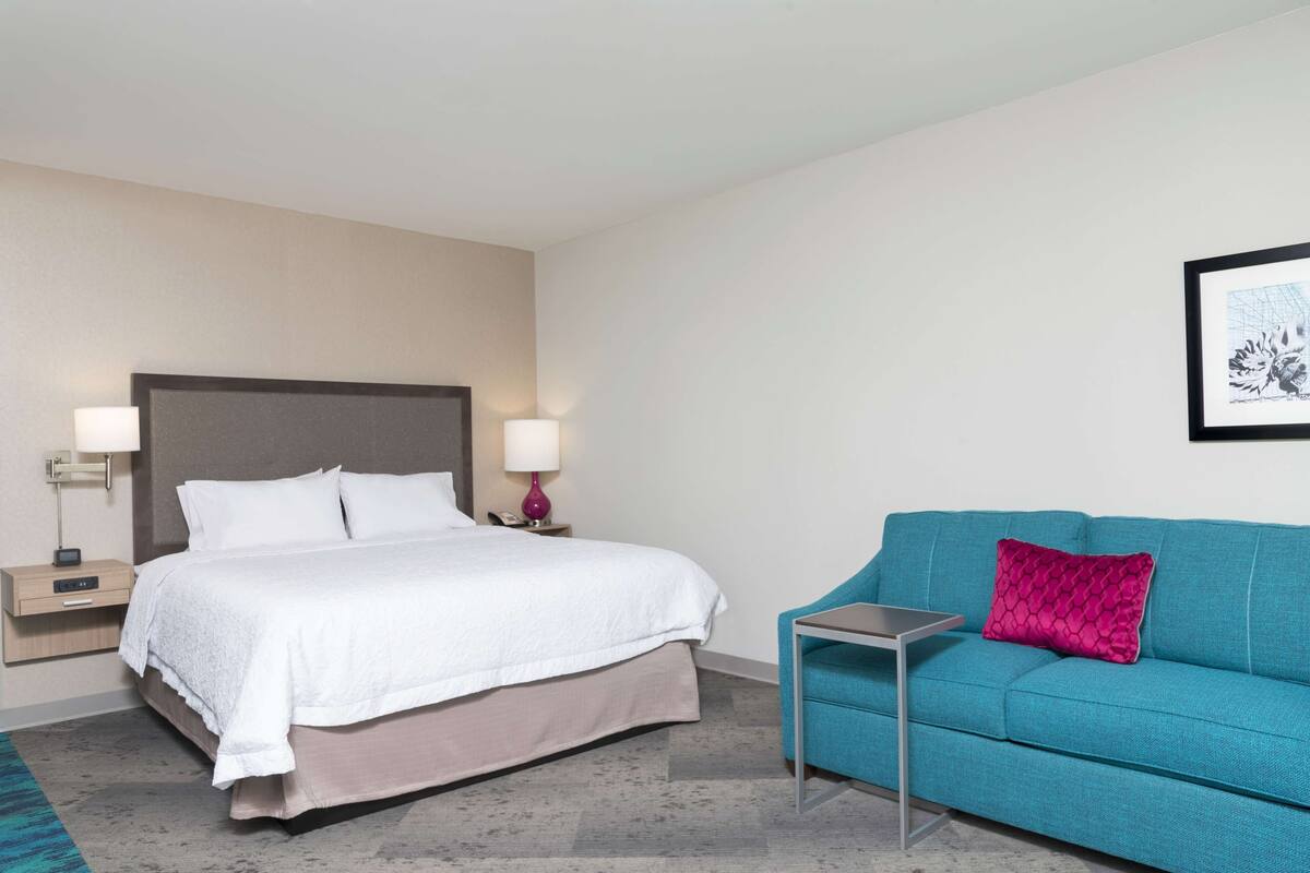 Une chambre d’hôtel comprenant un lit, des tables de chevet, une petite table de nuit, un canapé et une petite table.