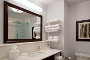 A modern bathroom with a large mirror, white sink, and neatly arranged towels.