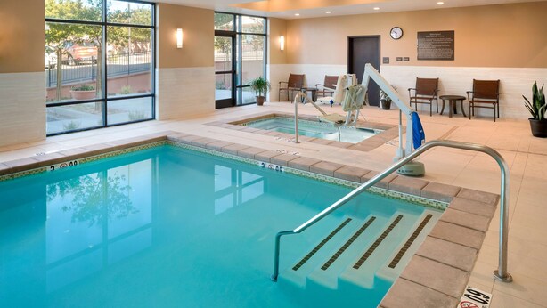 An indoor swimming pool with clear water, a lifeguard chair, and a seating area with chairs and a table. - Hampton Inn Kanab (Kanab)