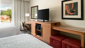 A hotel room with a bed, a desk with a television, a microwave, and a red suitcase. - Hampton Inn Kanab (Kanab)