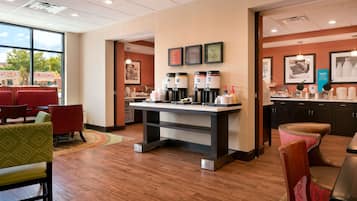 A modern hotel lobby with a coffee bar, seating area, and artwork on the walls.