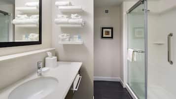 Un bagno moderno con un lavandino grande, uno specchio e uno spazio doccia in vetro.