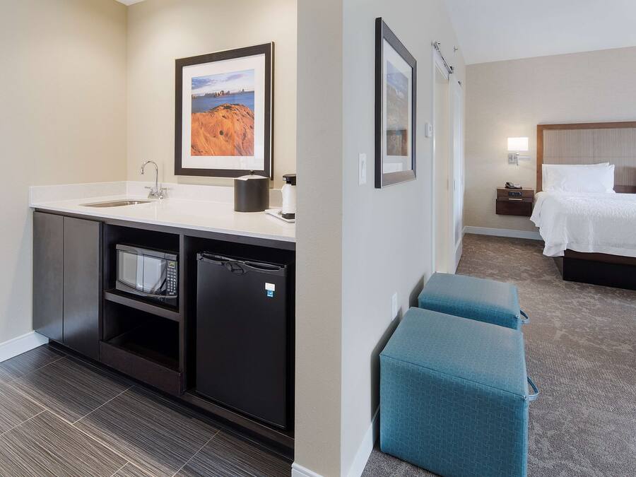 Una habitación de hotel con cama, mesita de noche y una pequeña zona de estar.