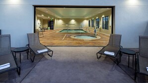 A pool area with two lounge chairs and a pool table, surrounded by walls with windows and a door.