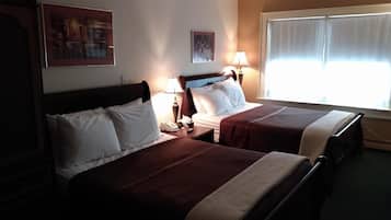 Habitació d'hotel amb dos llits, una tauleta de nit amb telèfon, dues làmpades penjades a la paret i una finestra amb cortines.