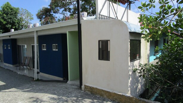 Una hilera de edificios de una planta con puertas y ventanas individuales, algunos con contraventanas.