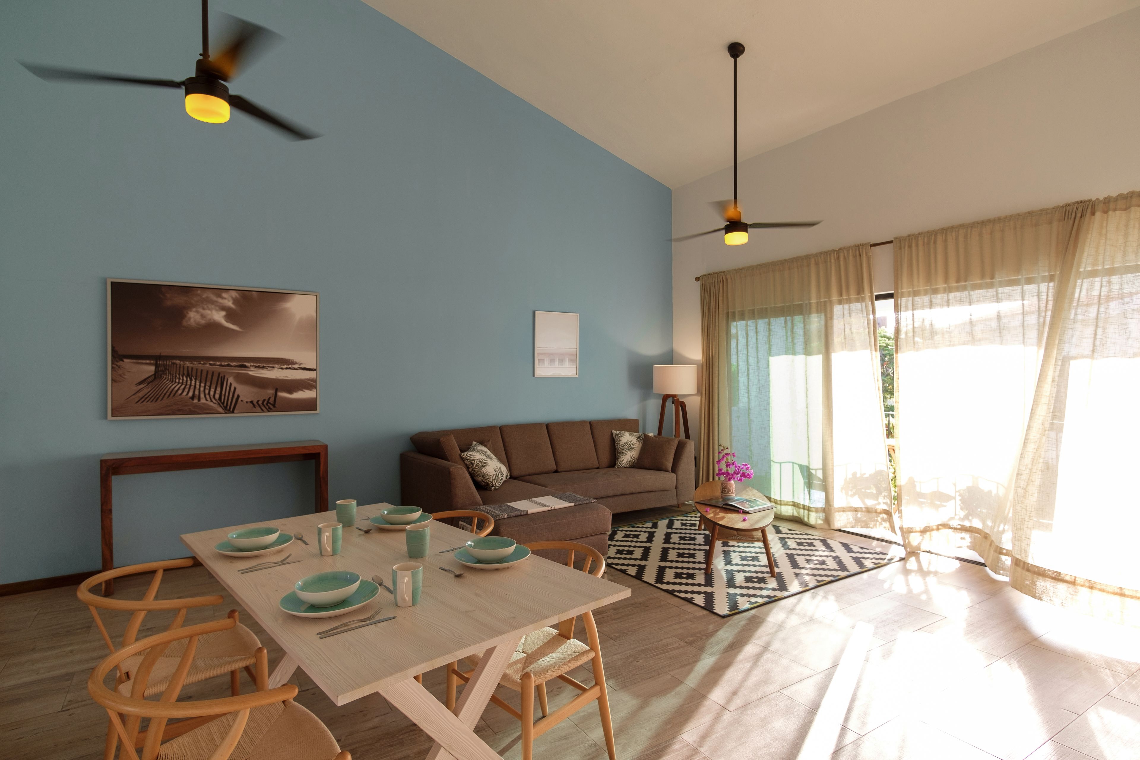 A living room with a dining table, sofa, and ceiling fans.