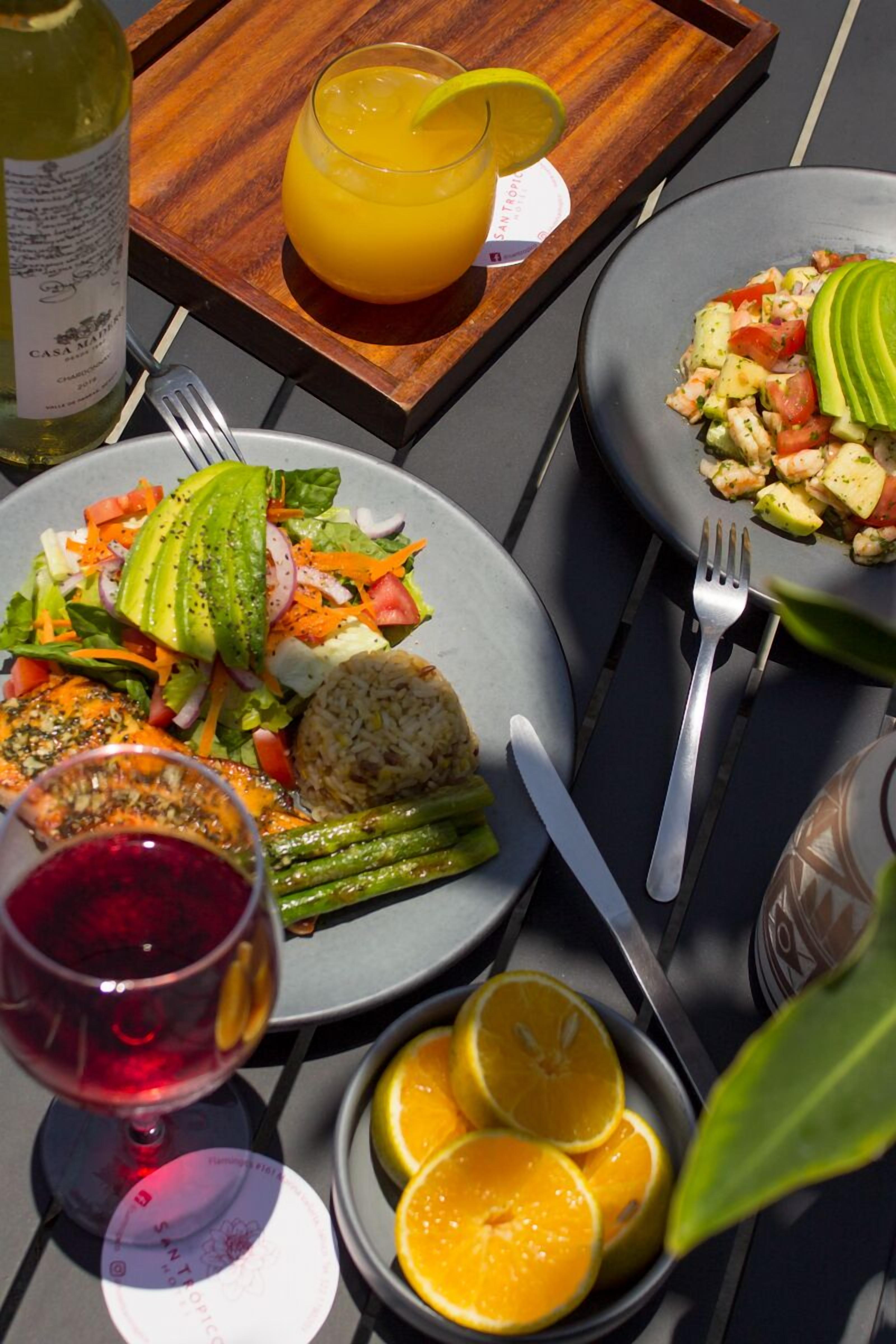 Mesa posta com pratos de comida, uma garrafa de vinho e copos de suco de laranja.