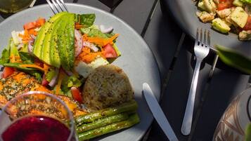 Mesa posta com pratos de comida, uma garrafa de vinho e copos de suco de laranja.