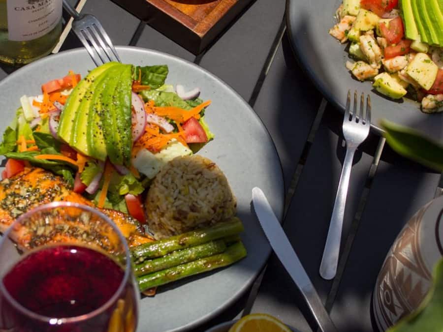 Mesa posta com pratos de comida, uma garrafa de vinho e copos de suco de laranja.