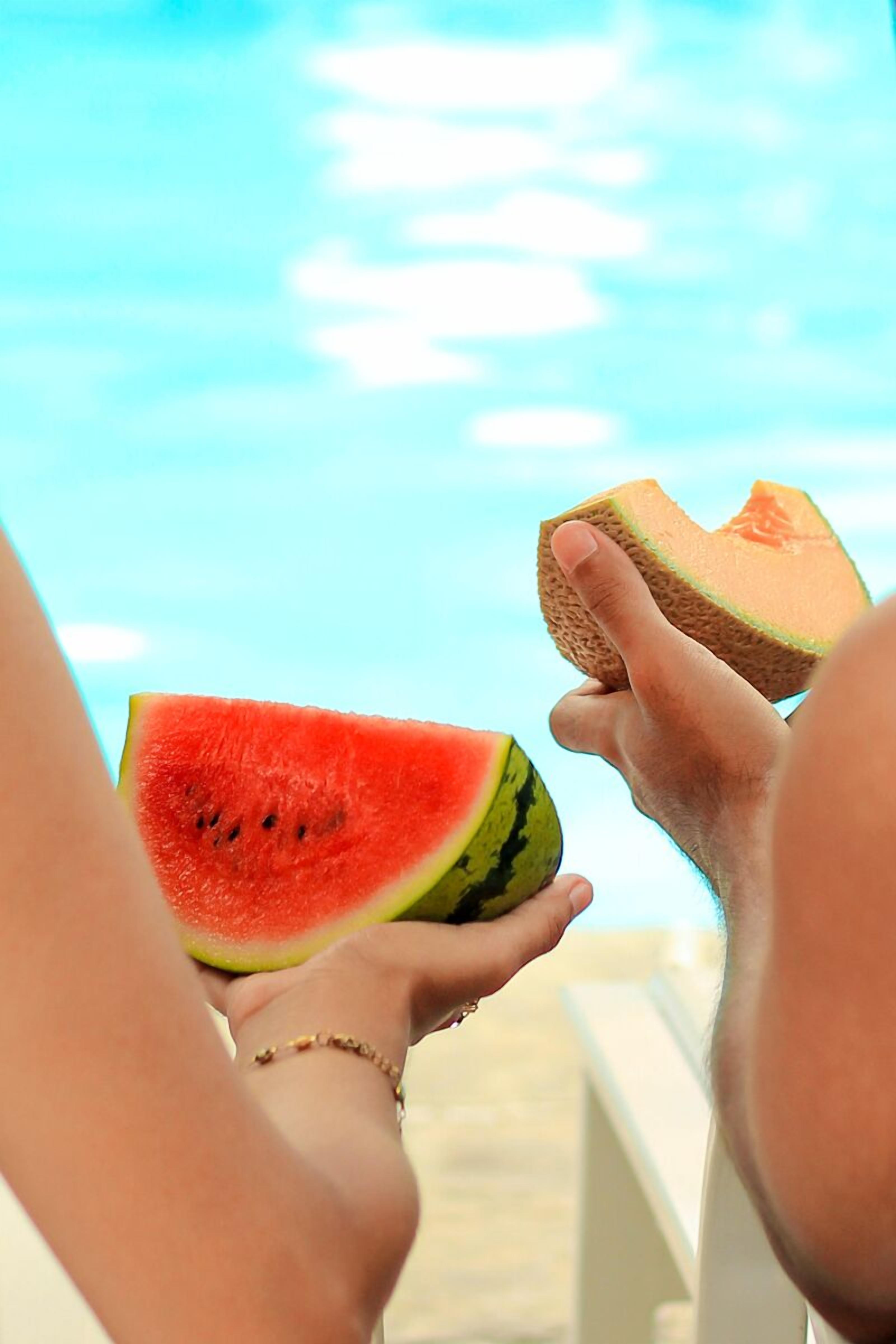 A person holding a slice of watermelon and a melon.