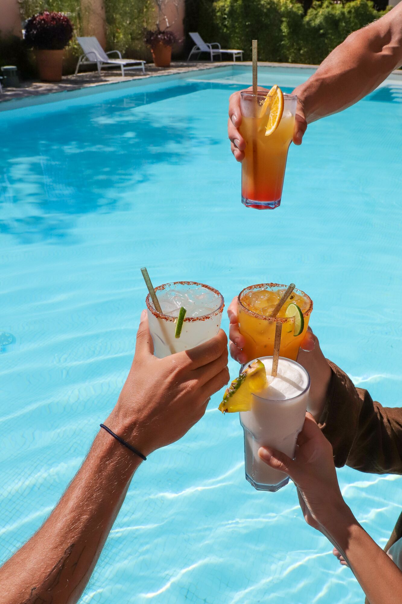 Folk nyder drinks ved en pool.