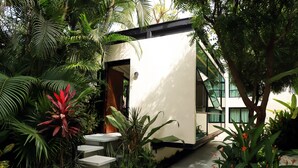 A modern building with a white exterior, surrounded by lush greenery and a stone pathway leading to the entrance. - San Trópico Boutique Hotel & Peaceful Escape (Puerto Vallarta)
