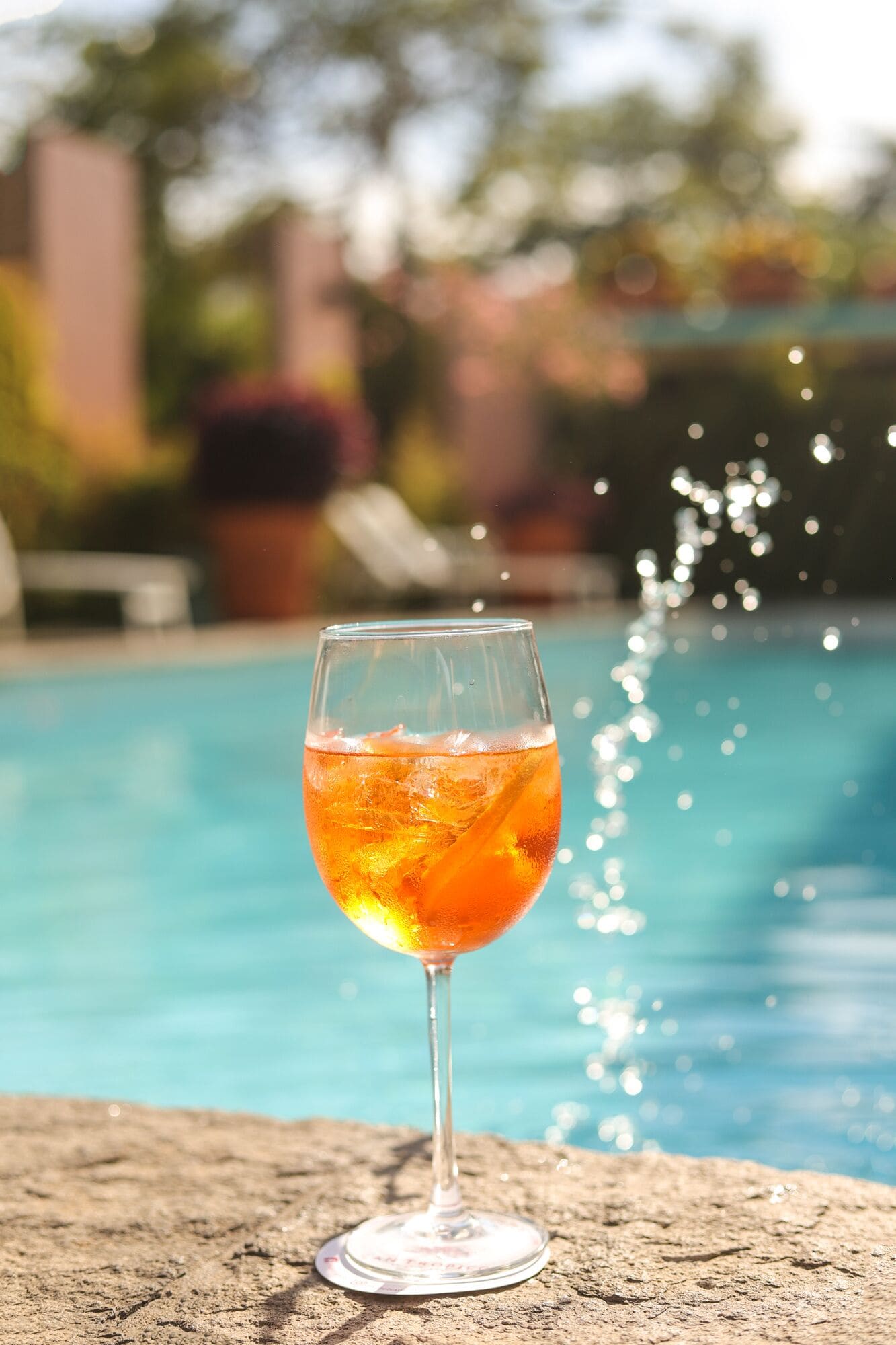 Un verre de boisson à l’orange au bord d’une piscine, avec de l’eau qui éclabousse.