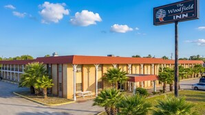 Un motel con tetto rosso, palme e un cartello con la scritta The Woodfield Inn.