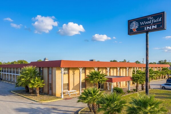 Ein Motel mit rotem Dach, Palmen und einem Schild für The Woodfield Inn.