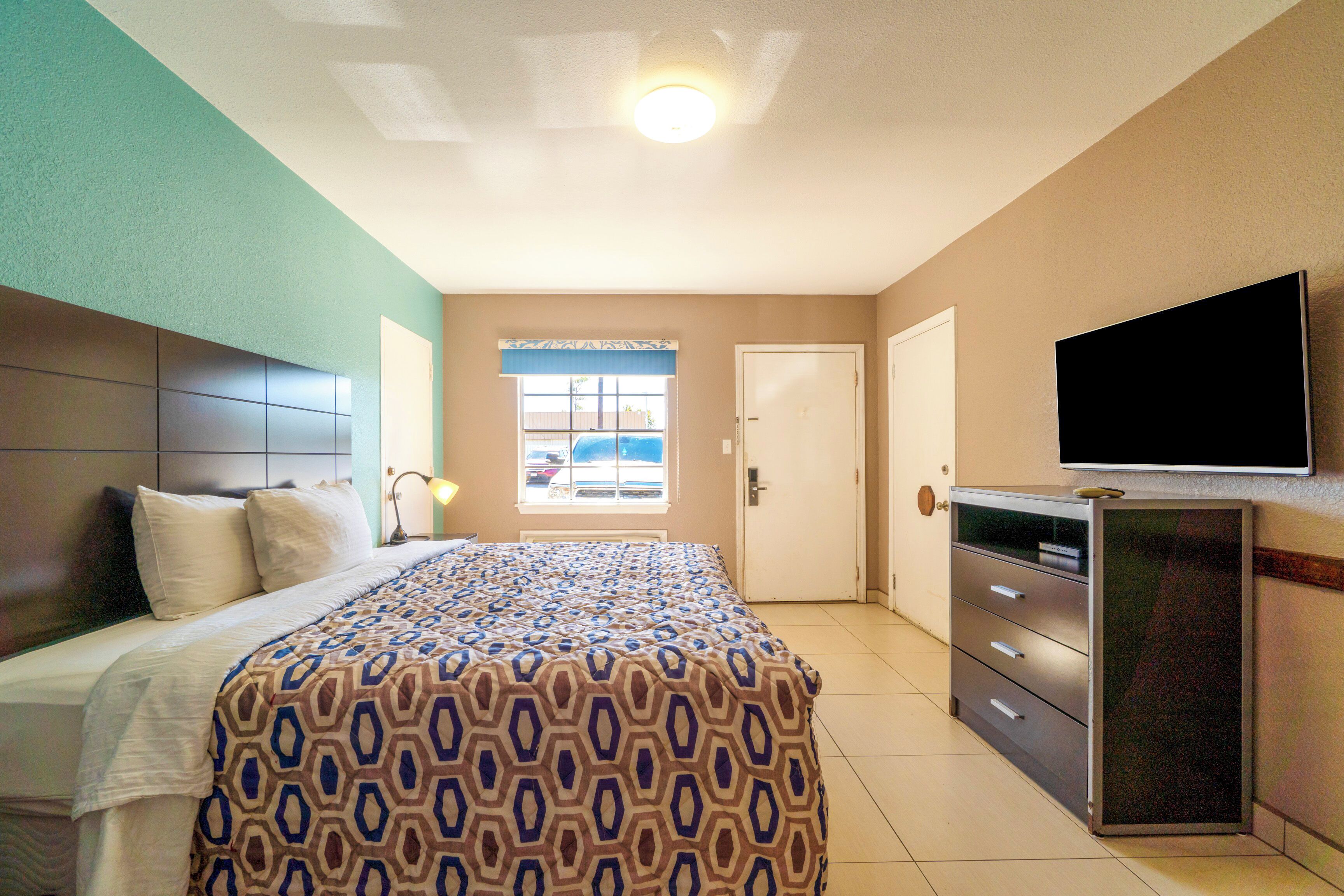A hotel room with a bed, a desk, a television, and a window with a view.