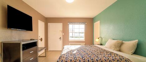 Un dormitorio con cama, cómoda, televisor y ventana con vistas.