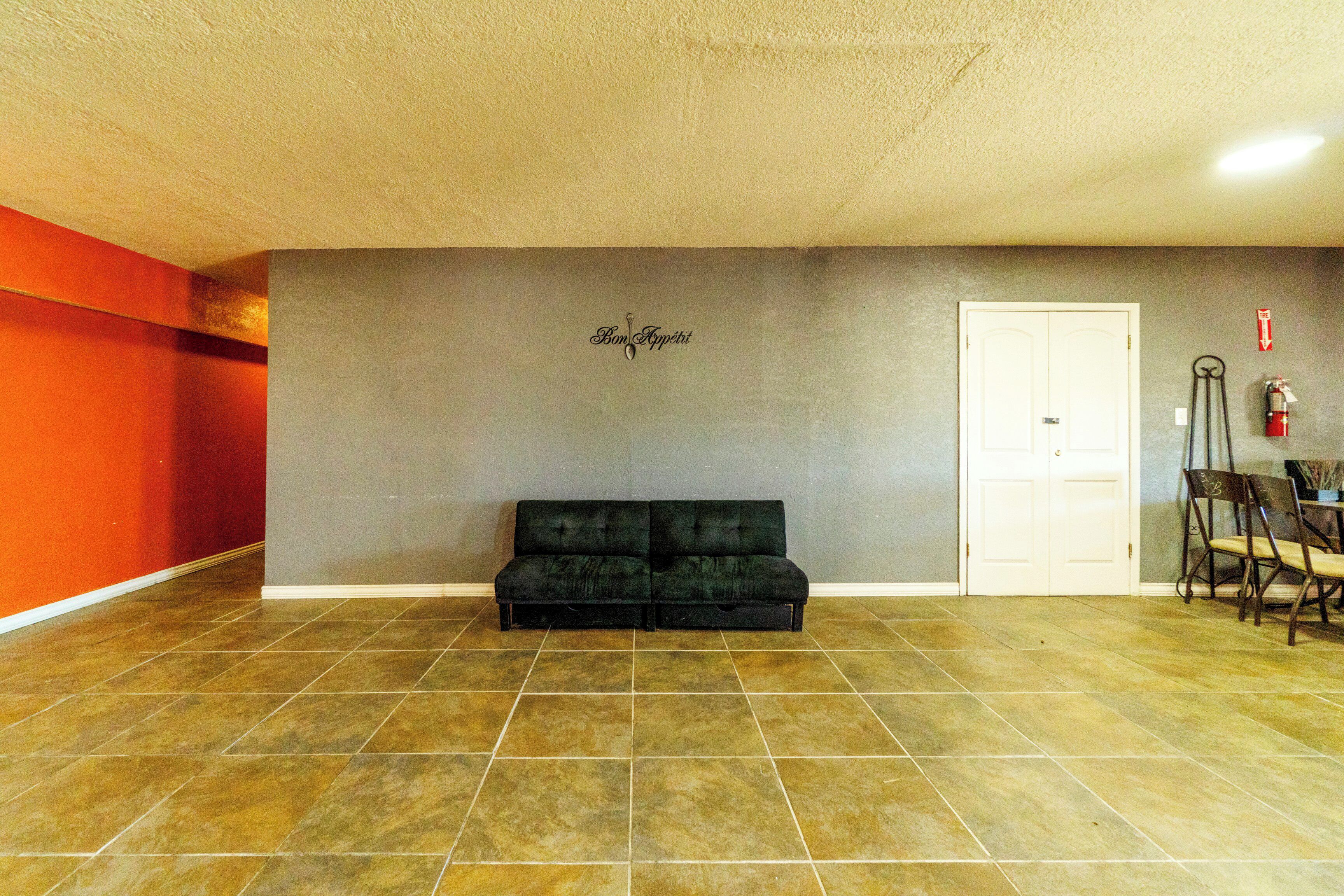 A room with a black sofa, a white door, and a fire extinguisher on the wall.