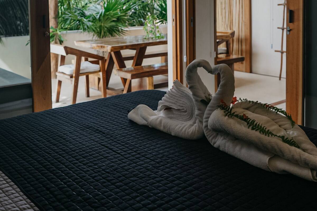 A bedroom with a bed, a ceiling fan, and a view of an outdoor patio with a table and chairs.