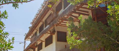 A traditional building with a thatched roof, surrounded by lush greenery.