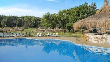 Ein Swimmingpool mit Liegestühlen und Reetdach-Sonnenschirmen.