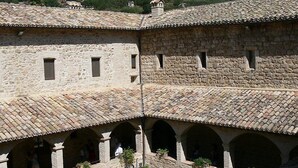 A stone building with a courtyard, featuring arches and potted plants. - Hotel Mom Assisi (Assisi)