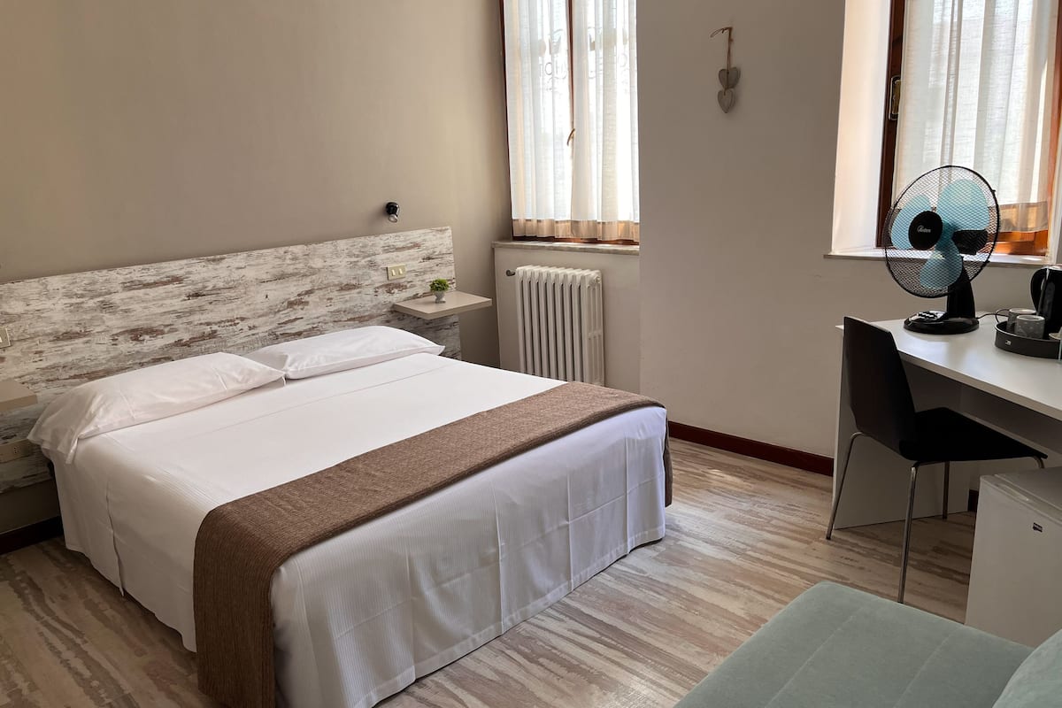 A bedroom with a bed, bedside table, and a desk with a chair.