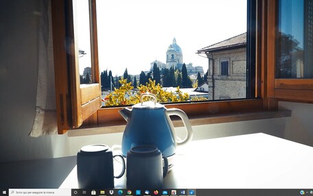 A view from a window with a kettle and two mugs on a table.