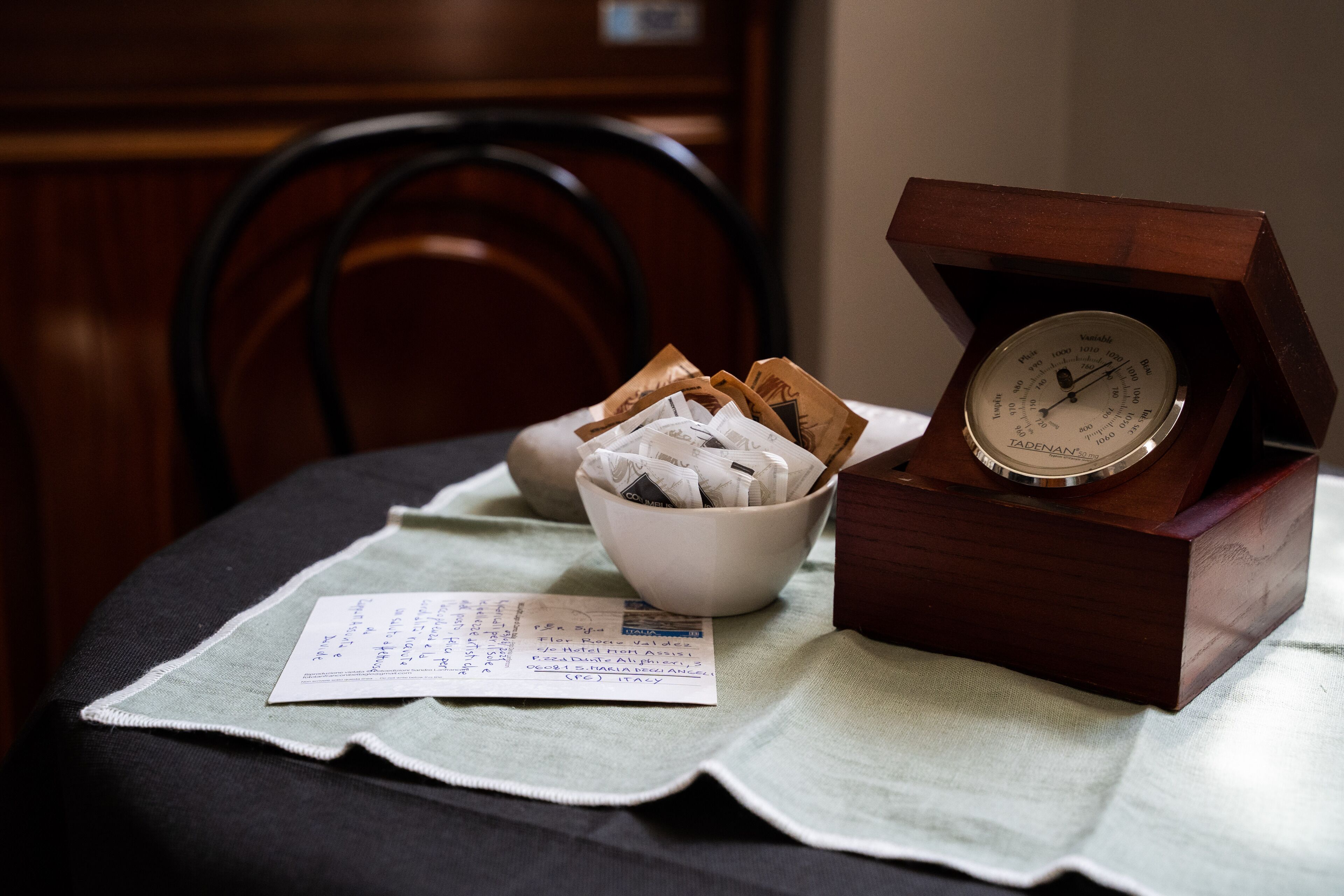 Una caja de madera con un dial, un cuenco con sobres y un recibo sobre un mantel.