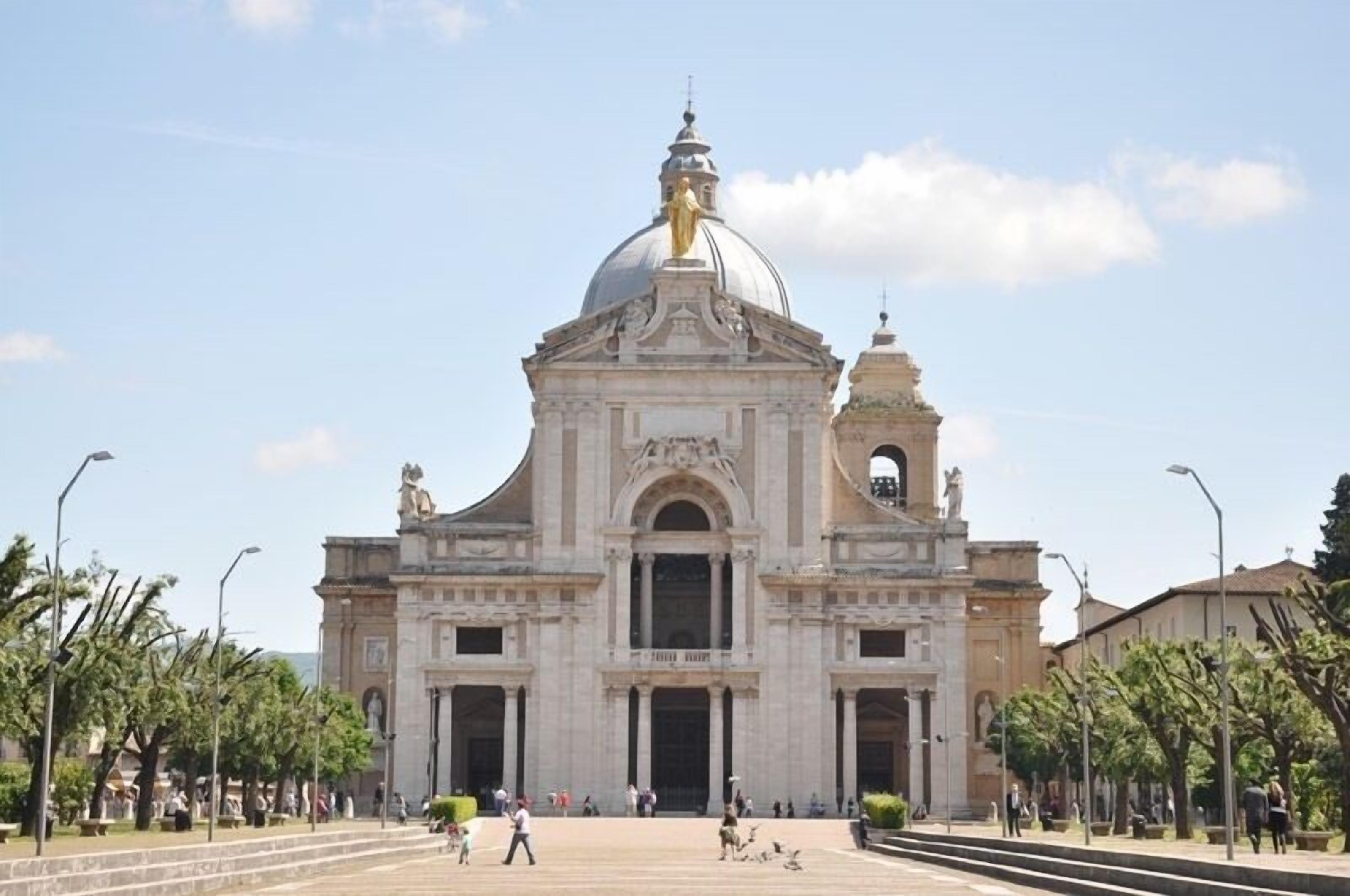 Un edificio grande e histórico con una cúpula destacada y estatuas, que presenta una entrada imponente y una amplia plaza.