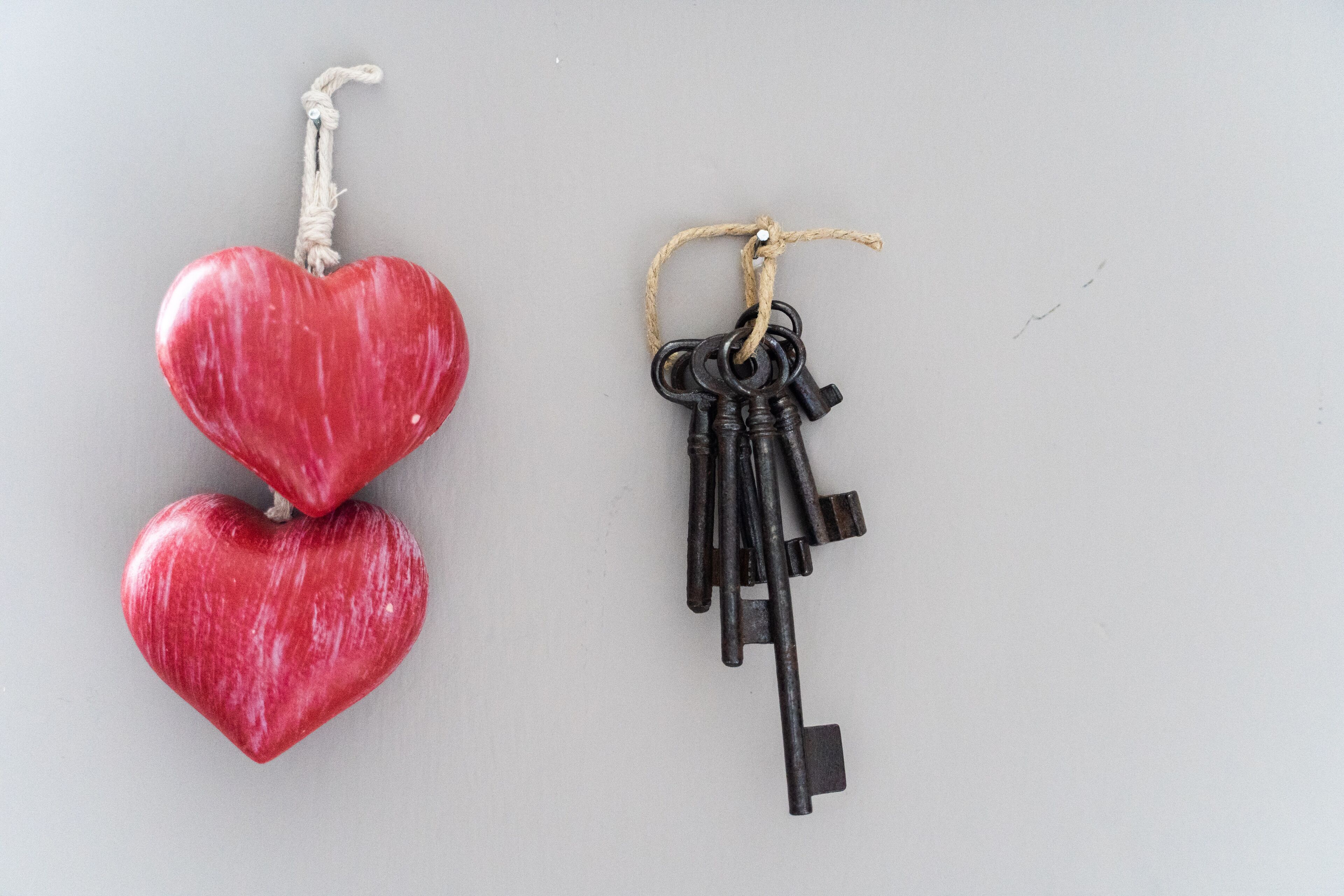 Two heart-shaped objects, one red and one black, hanging from strings.