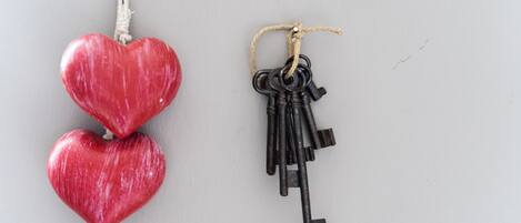Two heart-shaped objects, one red and one black, hanging from strings.