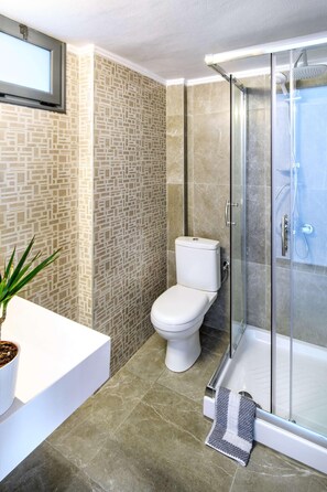 A bathroom with a toilet, shower, and a potted plant. - Philoxenia Hotel (Polygyros)